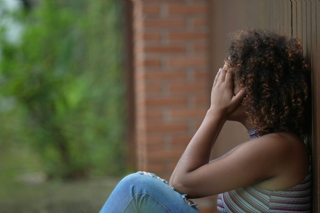 Menina encostada na parede, envergonhada.