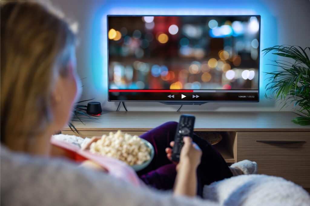 Mulher com um pote de pipoca na mão assistindo TV.