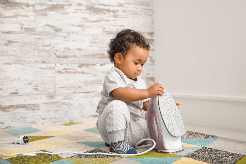 Criança colocando a mão em um ferro de passar roupa.