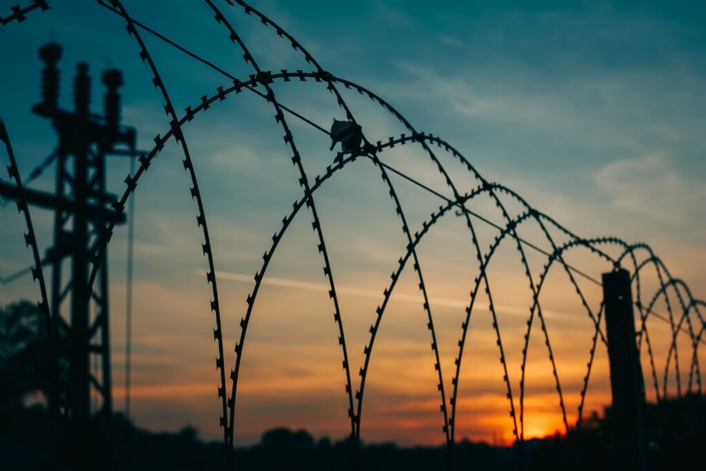 Cerca de arame com o sol se pondo ao fundo.