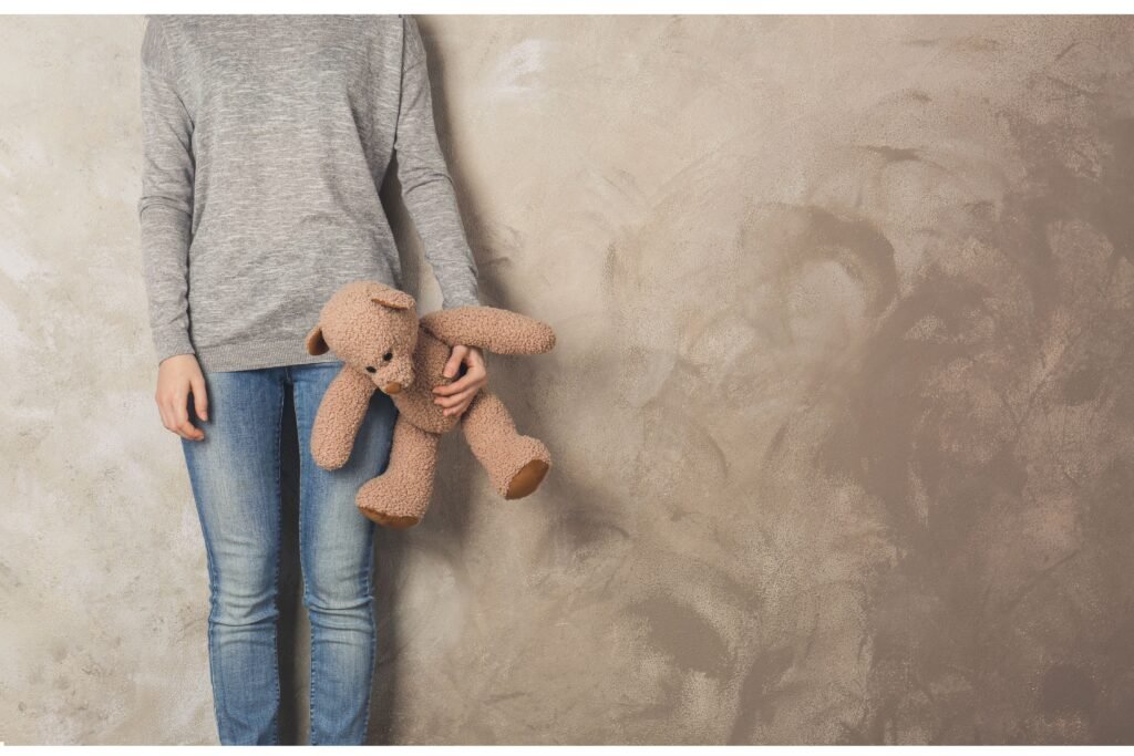 Criança com ursinho na mão.