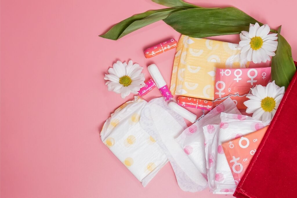 Fundo rosa com absorventese flores de camomila.