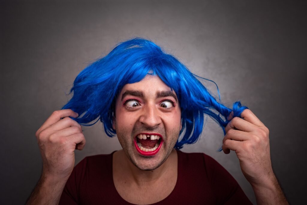 Homem banguela e de cabelo azul fazendo careta.