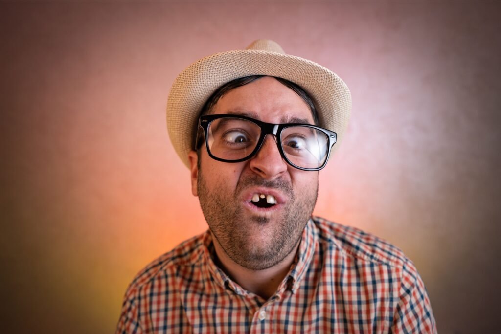 Homem sem dente de chapéu e óculos.