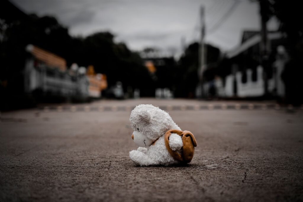Urso de brinquedo abandonado no meio de uma rua.
