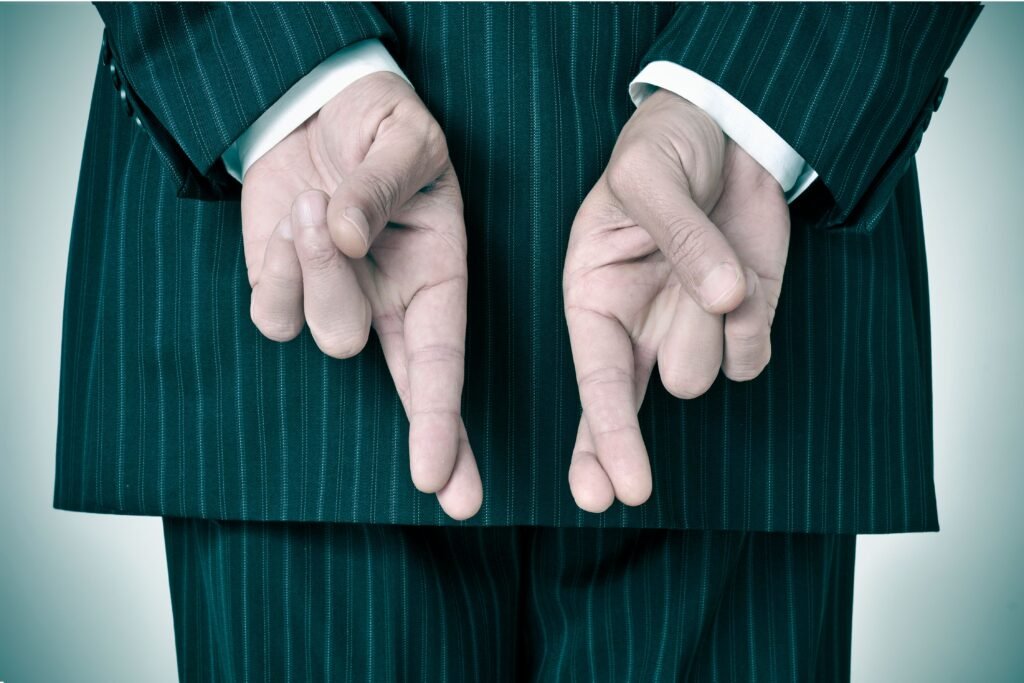 Pessoa de terno cruzando os dedos das duas mãos.