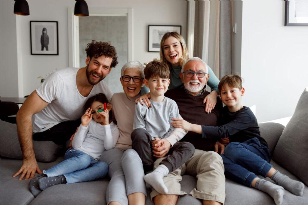 Família com mãe, pai, filhos e avós no sofá.